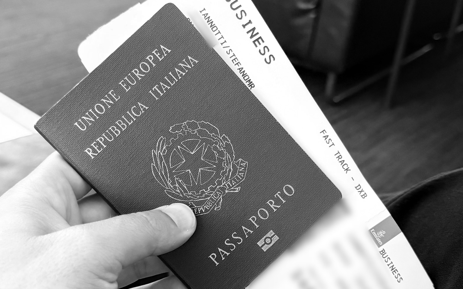 Stefano Iannotti holding his Italian passport and a business class boarding pass to Dubai